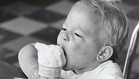 Small child eating an ice cream cone.