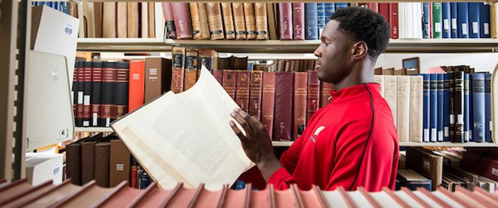 Nigel Hayes holding a book in the library.