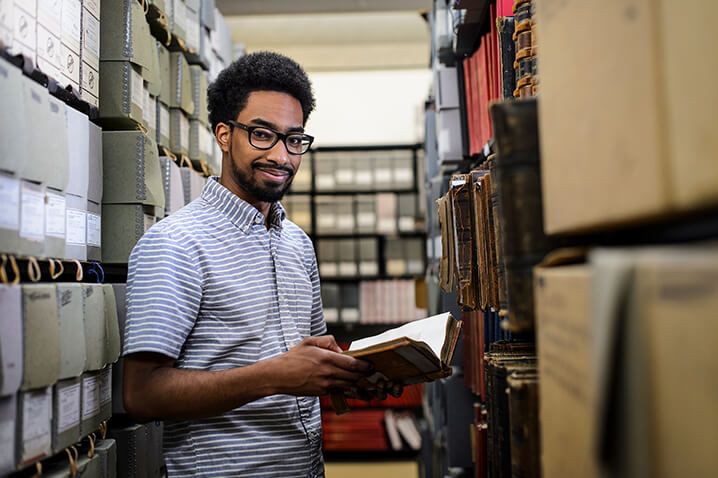 Harvey Long, a library and information studies graduate student, looks through University of Wisconsin photo albums from the 1870s and 1880s while doing research at University Archives and Records Management Service in Steenbock Library at the University of Wisconsin-Madison on April 21, 2016. Long's research, titled "Filed Under Negro: Documenting Black Students at the University of Wisconsin, 1875-1940," explores the early history of African-American students on campus. (Photo by Jeff Miller/UW-Madison)
