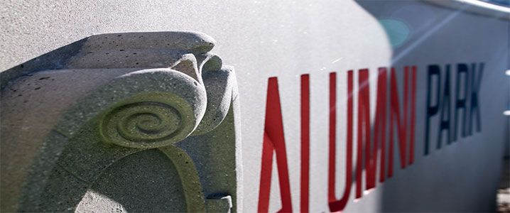Photo of the Alumni Park sign and University crest.