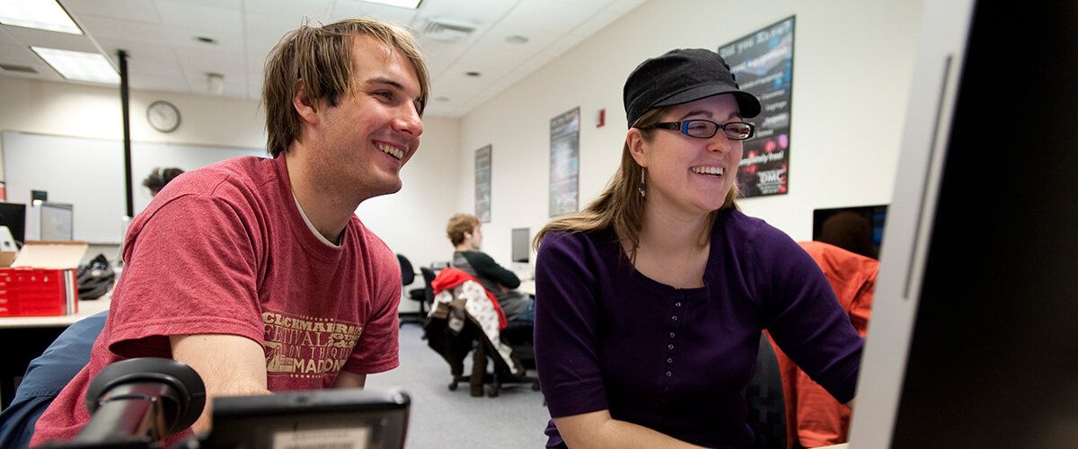 Two people smiling and looking at a computer screen