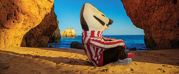 Bucky Badger sitting on beach in Brazil.